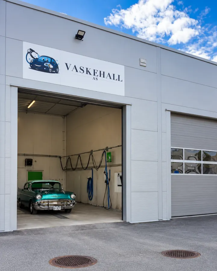 Vaskehall AS i Hensmoveien 8. Porten står åpen inn til en lys vaskehall med en grønn veteranbil inne.